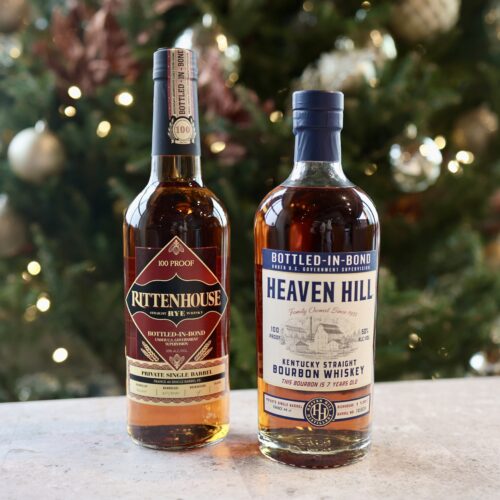 two bottles of whiskey sitting on a table in front of a christmas tree