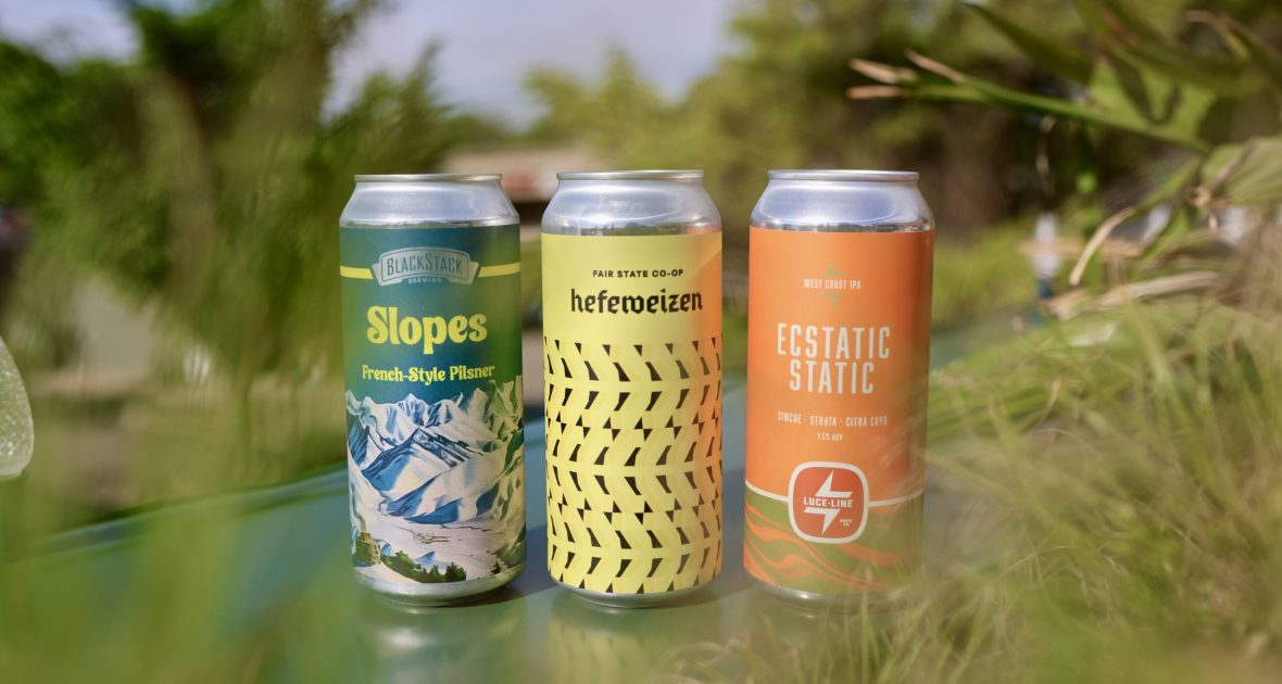 Three beer cans surrounded by greenery